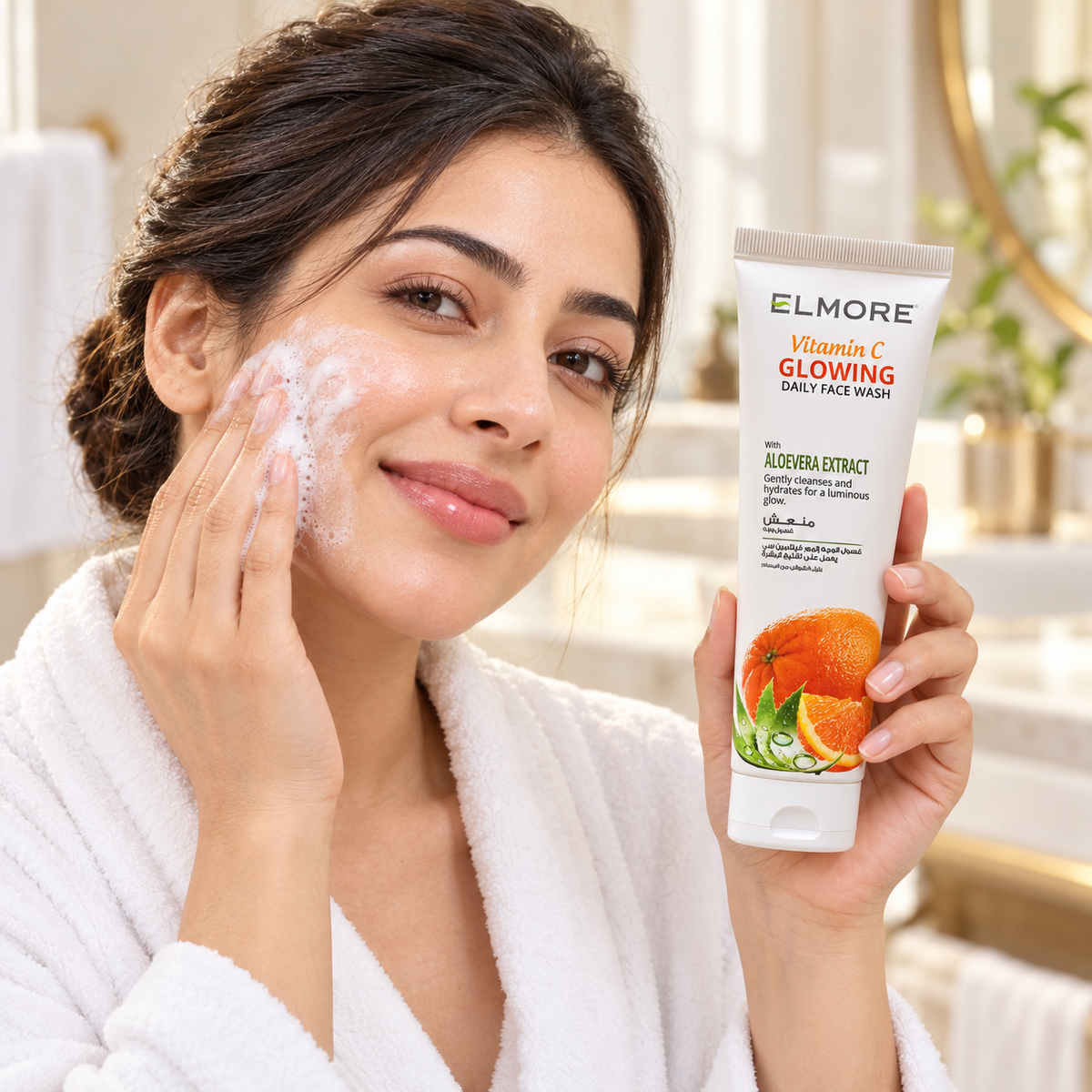 Woman applying foaming cleanser to her cheek while holding a tube of Elmore Vitamin C Glowing Daily Face Wash.